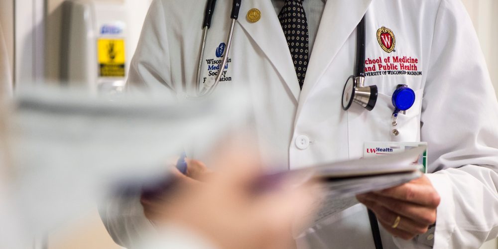 An embroidered W crest is pictured on a medical student’s white coat during floor rounds.