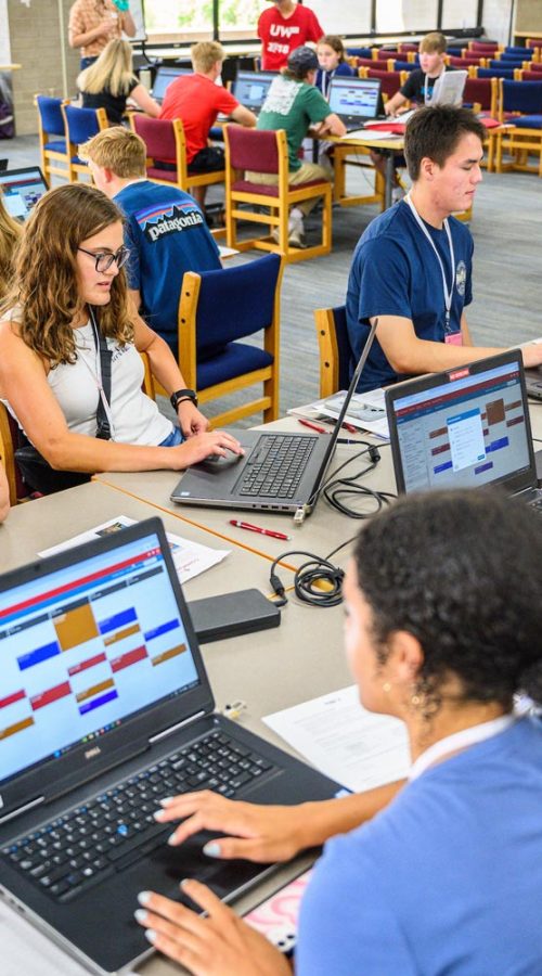 students registering for classes at laptop computers in a library