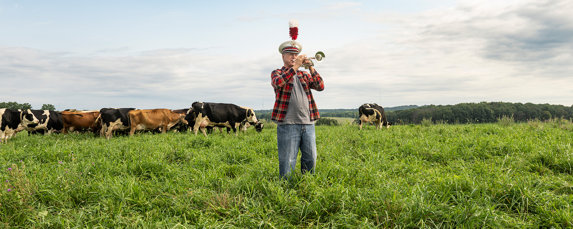 UW alum and former UW Marching Band member David Anderson plays a trumpet in a farm field