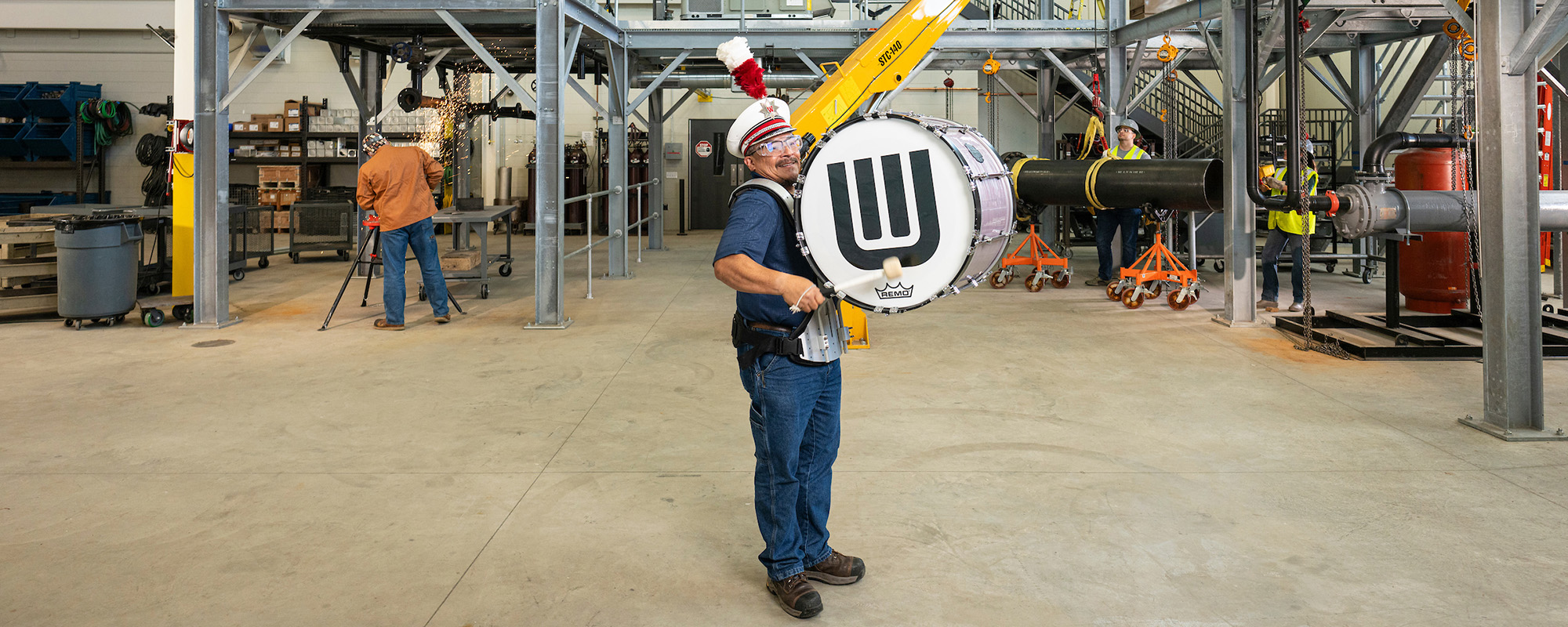 UW alum and former UW Marching Band member Rob Anchetta plays a bass drum in a steamfitters training facility